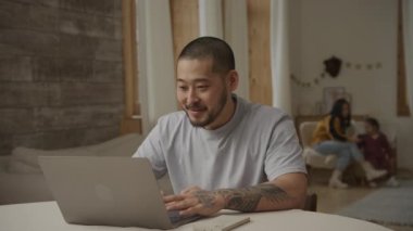 Karısı ve kızıyla birlikte bilgisayarında çalışan Asyalı heyecanlı bir baba.
