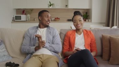 Afro-Amerikalı çift bir kanepede oturup sakin bir şekilde konuşarak evlerindeki oturma odalarında planlarını tartışıyor.
