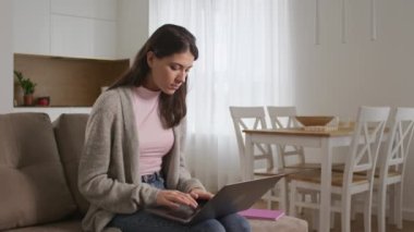 Genç kız öğrenci oturma odasında bir deneme yazıyor.