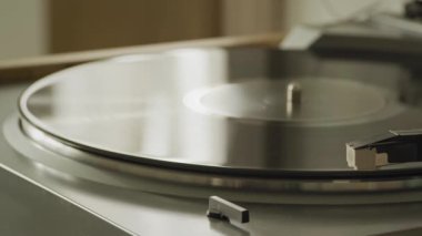 Playhead moves into place starting playback on a vinyl table at home with soft window reflections on it