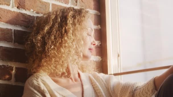 Curly Caucasian Woman Catching Sunlight Window Sill Indoors — 비디오