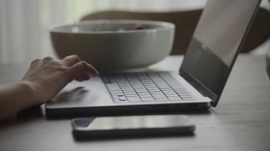 Close up pivoting around caucasian woman hand swiping on laptop computer touchpad while code review in slow motion