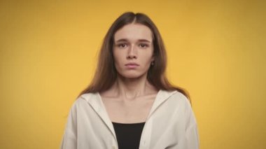 Woman taking a deep breath and exhale on a bright yellow background in studio in slow motion