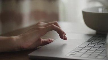 Close up of a caucasian woman hand swiping on a laptop computer touchpad indoors in slow motion