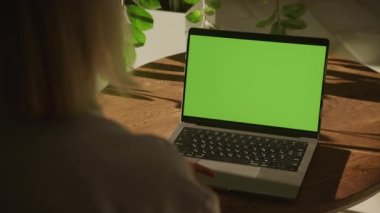 Beyaz bir kadının yeşil ekran krom anahtarı olan bir dizüstü bilgisayarı 90 fite yavaş çekimde izlediği el kamerası görüntüsü.