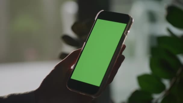 Pivoting Hand Holdig Smart Phone Green Screen Shade Indoors — Vídeo de Stock