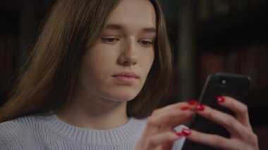 Close up of a caucasian woman browsing on smart phone while online shopping with various facial expressions
