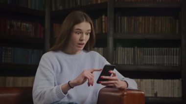 Close up caucasian woman browsing on smart phone online getting excited recieving shocking good news in slow motion indoors