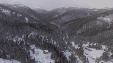 Aerial view flying over forests in the mountains in wintertime outside