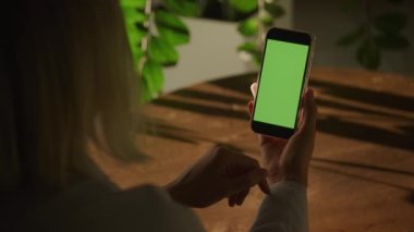 Handheld close up of a woman holding vertical smart phone with green screen chroma key in 90fps slow motion
