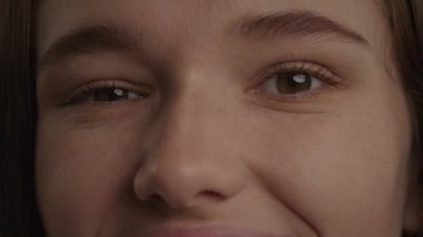 Close up of a caucasian woman eyes in a wink or blink gesture in slow motion indoors