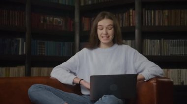 Caucasian student woman waving hand in a goodbye gesture on a video call on her laptop indoors