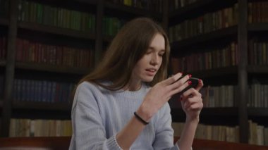 Close up of a caucasian woman playing concentrated game on her smart phone in slow motion indoors