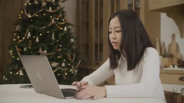 Young adult 20s asian woman browsing unhappy on her laptop online during new year eve indoors