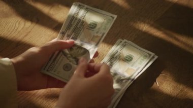 Handheld close up of caucasian woman hands counting money in slow motion 100 dollar bill