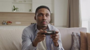 Young adult guy playing console game and celebrates a win indoors