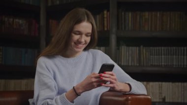 Close up of a caucasian woman texting and flirting on her smart phone indoors in slow motion