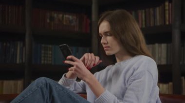 Close up of a caucasian woman browsing on her smart phone online in doubt thinking on a decision indoors