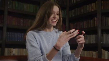 Close up of a caucasian woman celebrate win in online game on her smart phone in slow motion indoors