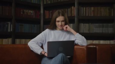 Slow optical zoom out caucasian woman student thoughtful working on a laptop indoors in slow motion
