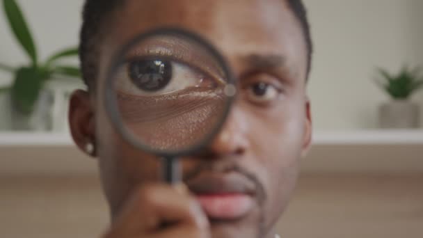 Voksen Afrikansk Amerikansk Mand Kigger Gennem Forstørrelsesglas Ind Kameraet Indendørs – Stock-video