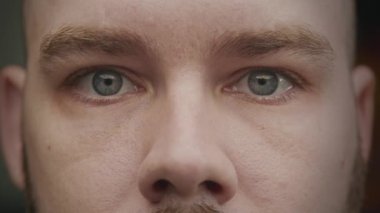 Close up shot of caucasian adult man blue eyes looking from side to side in slow motion