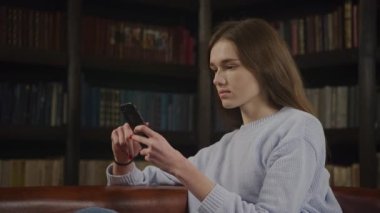 Caucasian woman browsing online on smart phone showing various facial expressions indoors in slow motion