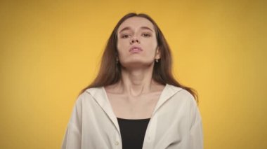 Woman taking a deep breath and exhale on a bright yellow background in slow motion