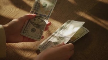 Handheld close up of caucasian woman hands counting money in slow motion 100 dollar bill