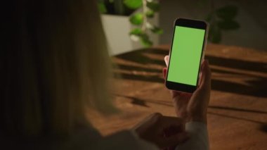 Handheld close up of a woman holding smart phone with green screen chroma key and doing a single swipe with her finger in slow motion