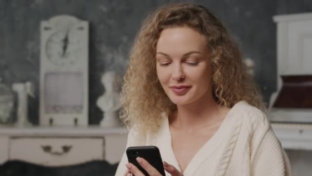 Young Curly Caucasian Woman Typing Her Smart Phone Indoors — Video Stock