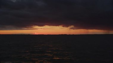 Static scenic landscape of a river with storm sky an a distant rain on sunset in slow motion outside