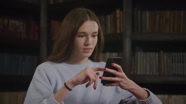 Close up of a caucasian woman browsing on her smart phone and laughing indoors in slow motion