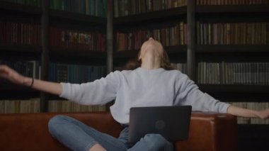 Young adult caucasian woman recieving good news on her laptop computer indoors in slow motion
