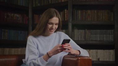 Slow optical zoom out caucasian woman texting and flirting on her smart phone indoors