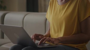 Close up camera pan showing African American woman portrait typing on her laptop keyboard in slow motion indoors