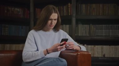 Close up of a caucasian woman browsing on her smart phone thoughtful in doubt indoors in slow motion