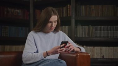 Close up of a caucasian woman browsing on her smart phone thoughtful in doubt indoors in slow motion