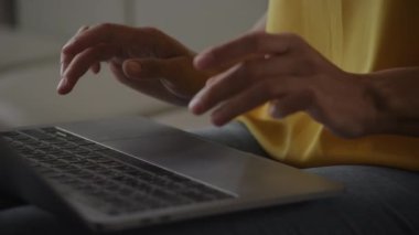 Close up of an African American woman hands typing on a laptop keyboard handheld pivotion around in slow motion