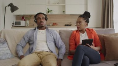 Afro-Amerikalı çift bir kanepede oturup sakin bir şekilde konuşarak evlerindeki oturma odalarında planlarını tartışıyor.