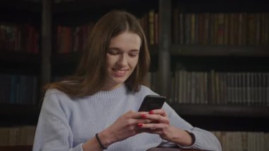 Kafkasyalı bir kadının akıllı telefonuyla mesaj atarken, yavaş çekimde gülümsemesini kapat.