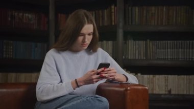 Kafkasyalı bir kadının akıllı telefonuna yavaş çekimde ciddi bir şekilde göz gezdirirken onaylayarak başını sallamasını yakın çekim.