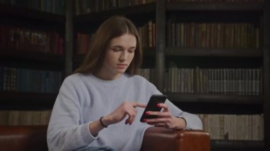 Kafkasyalı bir kadının akıllı telefonuna göz gezdirirken ve içeride duygularıyla gülümserken.