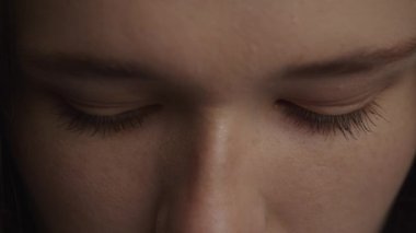 Close up of a caucasian woman raising up her head and open her eyes in slow motion front view