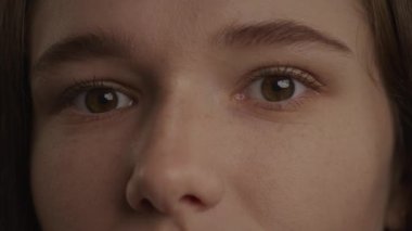 Close up of a caucasian woman eyes in a wink or blink gesture in slow motion indoors