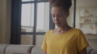 Genç, Afro-Amerikan bir kadının laptopuyla içeride çalışırken derin bir nefes alışına yakın durun.