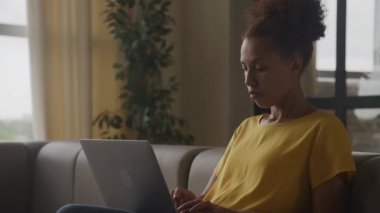 Afrika kökenli Amerikalı bir kadının el kamerasıyla çekilmiş. Düşünceli ve düşünceli bir şekilde dizüstü bilgisayarında yavaş çekimde karar verirken.