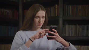 Genç beyaz kadın yavaş çekimde duygularıyla online alışveriş yaparken akıllı telefonuna göz atıyor.