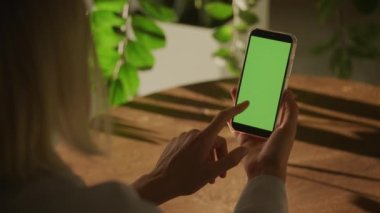 Elinde akıllı bir telefon tutan ve 90 fps yavaş çekimde yeşil ekran krom anahtarı olan bir kadının el kamerası.