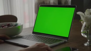 Krom anahtar yeşil ekranlı dizüstü bilgisayarın etrafında dönen el kamerası görüntüsü ve kadın elleri yavaş çekimde evde dinleniyor.